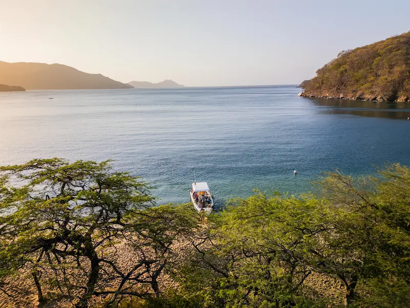 Atardecer en Bahía Concha con lancha y vegetación Tayrona